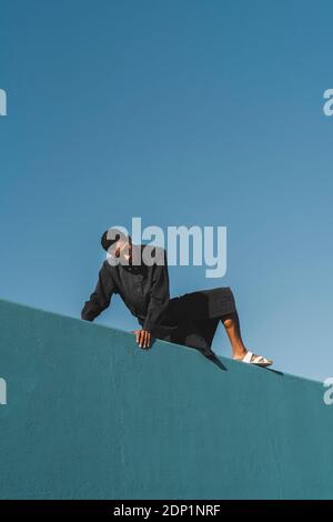 Junger Mann mit schwarzem Kaftan an der blauen Wand Stockfoto