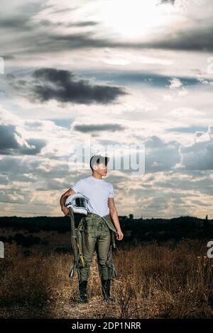 Man posiert als Astronaut auf einer Wiese mit dramatischen Wolken im Hintergrund gekleidet Stockfoto