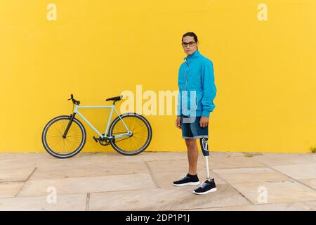 Mann, der auf einem Fußweg gegen die gelbe Wand steht Stockfoto