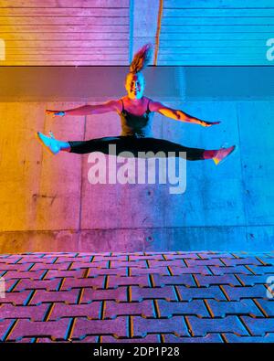 Junge Frau mit ausgestreckten Armen und gespreizten Beinen Wand Stockfoto