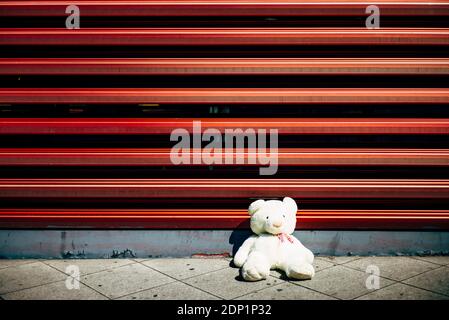 Einsamer Teddybär, der an der roten Wand Stockfoto