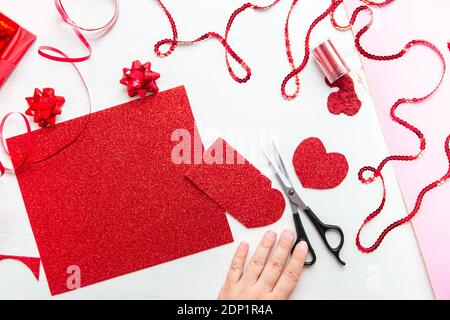 Valentinstag Scrapbook, Hochzeit oder andere Feiertag Dekorationen Hintergrund. Handgemachte Geschenk Grußkarte erstellen, schneiden. Die Hände der Frauen halten die Stockfoto