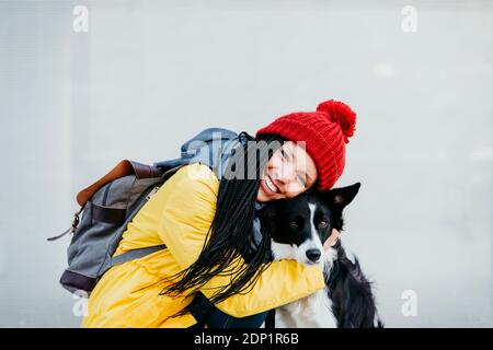 Glückliche Frau umarmt Haustier Hund gegen Wand Stockfoto