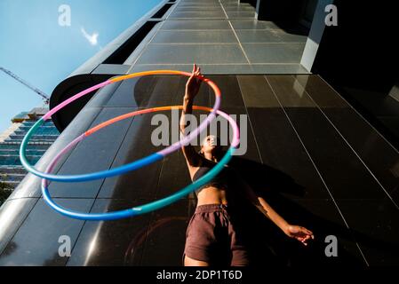 Sportliche Frau mit Kunststoffreifen außerhalb des modernen Gebäudes trainieren Stockfoto