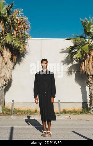 Junger Mann mit schwarzem Kaftan auf einer Straße stehend Stockfoto