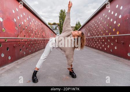 Frau mit gestreckten Armen beim Tanz auf Brücke in der Stadt Stockfoto