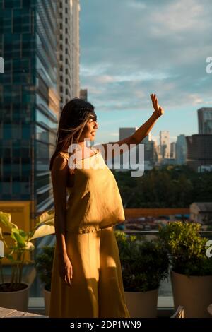 Frau, die auf der Dachterrasse, von wo wir den Sonnenuntergang, Bangkok, Thailand Stockfoto