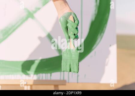 Junge Frau auf trockenem Feld, mit grüner Farbe auf Leinwand malen Stockfoto