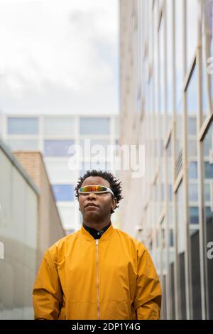 Porträt eines älteren Mannes mit gespiegelten Sonnenbrillen und gelber Jacke in der Stadt Stockfoto