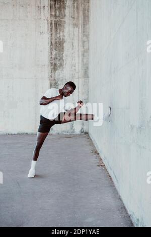 Männlicher Athlet, der an der weißen Wand trainiert Stockfoto