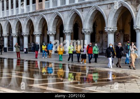 Eine Tour-Gruppe auf dem Markusplatz während Acqua Alta (hohe Flut), Venedig, Italien. Stockfoto