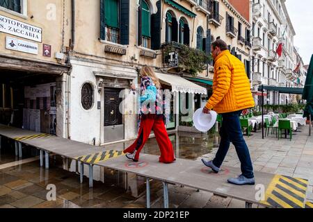 Touristen, die auf EINER erhöhten Plattform während Acqua Alta (hohe Tide) in der Nähe des Markusplatz, Venedig, Italien. Stockfoto
