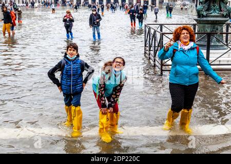 Visitors Wearing Water Protective Plastic Shoe Covers In St Mark’s Square During Acqua Alta (High Tide), Venice, Italy. Stock Photo