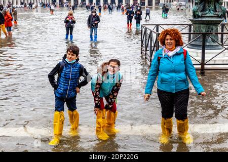 Visitors Wearing Water Protective Plastic Shoe Covers In St Mark’s Square During Acqua Alta (High Tide), Venice, Italy. Stock Photo