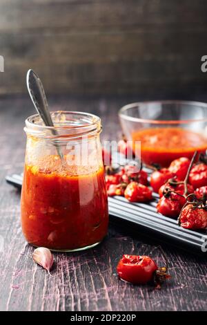 Tomatensauce und Zutaten auf dunklem Holzhintergrund. Stockfoto