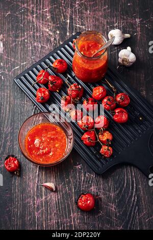 Tomatensauce und Zutaten auf dunklem Holzhintergrund. Stockfoto