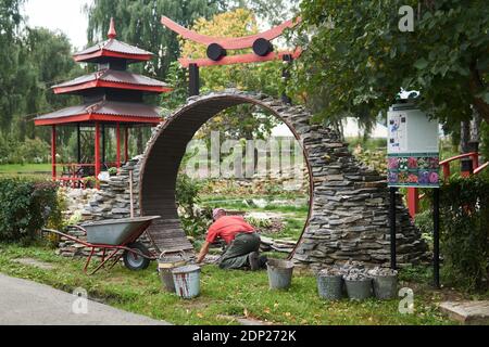 Perm, Russland - 01. September 2020: Arbeiter baut einen runden Eingang namens Mondtor in einem chinesischen Garten Stockfoto