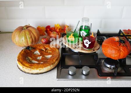 Hausgemachter Kuchen mit Getränken und Dekorationen für Halloween auf Lichtküche. Stockfoto