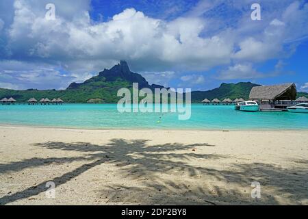 BORA BORA, FRANZÖSISCH-POLYNESIEN -7 DEZ 2018- Blick auf einen Palmenschatten auf dem Sand an der Lagune und Mount Otemanu im Le Meridien Bora Bora Resort in Stockfoto