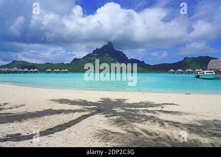 BORA BORA, FRANZÖSISCH-POLYNESIEN -7 DEZ 2018- Blick auf einen Palmenschatten auf dem Sand an der Lagune und Mount Otemanu im Le Meridien Bora Bora Resort in Stockfoto