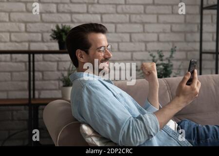 Junger Mann liegt auf der Couch schießen niedlichen Selfie auf dem Smartphone Stockfoto