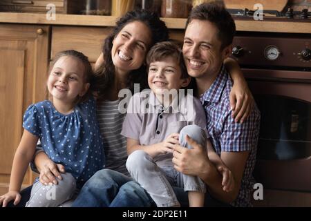 Paar mit Kindern posiert für Familienportrait drinnen Blick zur Seite Stockfoto