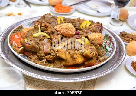 Traditionelle marokkanische gefüllte Hühnermahlzeit mit pommes Frites, Oliven, Zitrone, Brot auf dem Tisch Stockfoto
