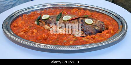 Marokkanisches Essen. Großer Fisch mit geschnittenem Tintenfisch gekocht. Und traditionelle Salate Stockfoto