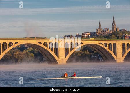 Am frühen Morgen Ruderer in Skiff am Potomac River, Key Bridge und Georgetown University im Hintergrund, Washington DC, USA. Stockfoto