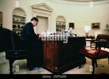 Präsident Ronald Reagan arbeitet 1985 am Resolute Desk im Oval Office. Dies war eine exklusive Session für eine Geschichte für ein Magazin, ich kann mich nicht erinnern, welche Publikation Foto von Dennis Brack bb 75 Stockfoto