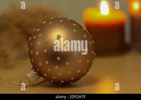 Eine Nahaufnahme eines goldenen Weihnachtsbaumspielzeug, einer brennenden Kerze und Pampas Gras vor einem verschwommenen Hintergrund. Weihnachtliche Atmosphäre im Inneren Details Stockfoto