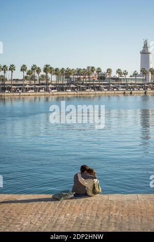 Verliebtes Paar im Hafen von Malaga mit Leuchtturm von Malaga, Muelle uno, Andalusien, Costa del sol, Spanien. Stockfoto