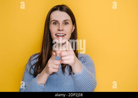 Erstaunt lustige Millennial junge Mädchen zeigt Finger zur Kamera, suchen große Augen überrascht Ausdruck, schockiert durch plötzlichen Erfolg, trägt Pullover Stockfoto