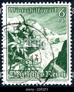 DEUTSCHLAND - UM 1938: Briefmarke gedruckt in Deutschland, Ausgabe Winterrelief, zeigt Großglockner (Österreich) und Edelweiss-Blume, um 1938 Stockfoto