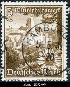 DEUTSCHLAND - UM 1938: Briefmarke gedruckt in Deutschland, Ausgabe Winterrelief, zeigt ein Schloss Forchtenstein (Österreich) und silberne Distelblume, um 1938 Stockfoto