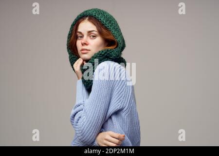 Frauen in einem gestrickten Kopfschmuck und in einem blauen Pullover Auf grauem Hintergrund gesundheitliche Probleme laufende Nase Stockfoto