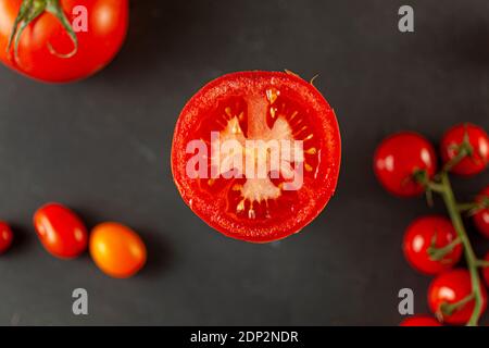 Ein selektives Nahaufnahme-Bild von oben einer geschnittenen Roma-Tomate mit Samen, die nach oben schauen. Im verschwommenen Hintergrund gibt es volle Kirsche an Stockfoto