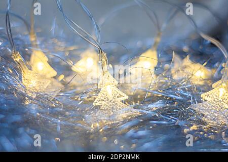 Weihnachten Lametta und elektrische Tannenbaum förmigen Girlande Licht auf Ein weißer gestrickter Hintergrund Stockfoto