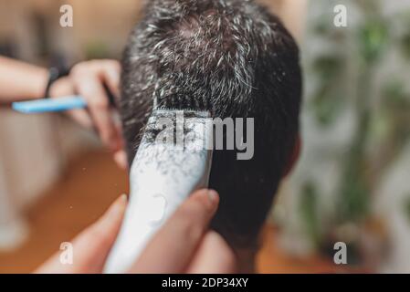 Frau, die Haarschnitt zu Mann mit elektrischen Trimmer. Stockfoto