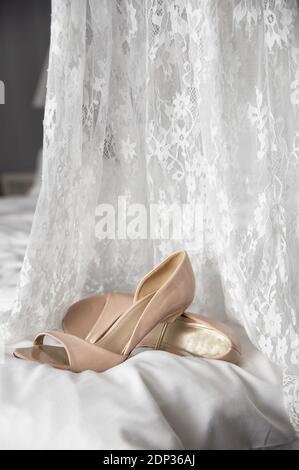 Hochzeitsschuhe auf dem Bett neben dem Kleid Stockfoto