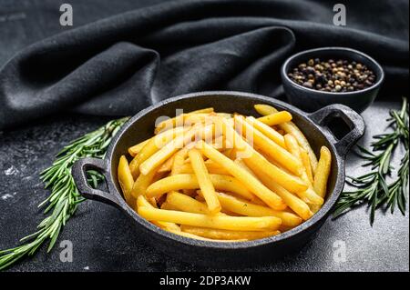 Pommes Frites, Pommes Frites mit Rosmarin in der Pfanne. Schwarzer Hintergrund. Draufsicht. Stockfoto