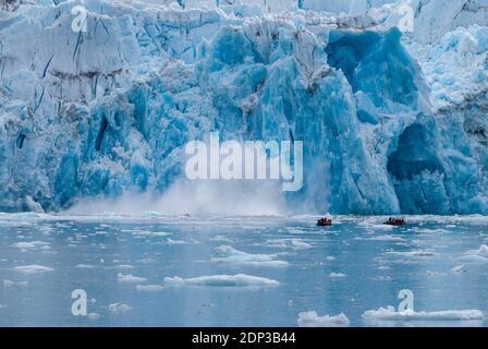 Gäste eines Kreuzfahrtschiffes in Zodiac Schlauchbooten beobachten einen Gezeitenwasser-Gletscher, der in Alaska aus nächster Nähe kalbt. Stockfoto