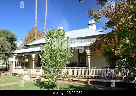 Australische 1920s Cottage mit Bull Nose der vorderen Veranda. Rauch driften von Chimney im Herbst. Stockfoto