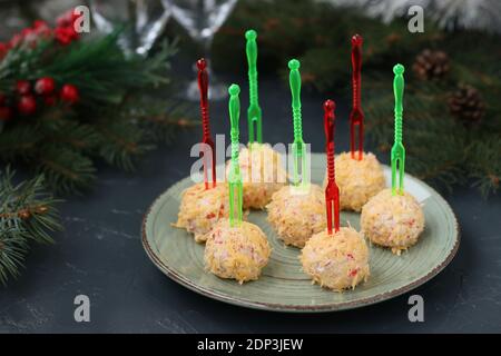 Kugeln aus Krabbenstäbchen und Käse in Käsespäne auf dunklem Hintergrund. Festlicher Snack zu Weihnachten und Neujahr. Stockfoto