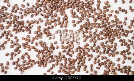 Duftende geröstete Kaffeebohnen. Kaffeebohnen auf weißem Hintergrund, besprüht Kaffee, Getreideernte, Draufsicht, auf weißem Hintergrund. Stockfoto