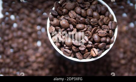 Duftende geröstete Kaffeebohnen. Duftende geröstete Kaffeebohnen in einer Plastikbecher innen, Draufsicht, Nahaufnahme. Stockfoto