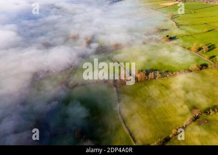 Luftaufnahme mit Blick auf landwirtschaftliches Ackerland und ein Tal Gefüllt mit einer Nebeldecke (Wales, UK) Stockfoto