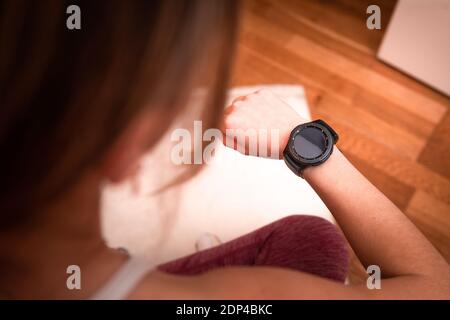 Junge kaukasische Frau beim Betrachten der Sportuhr während des Tuns Übungen zu Hause Stockfoto
