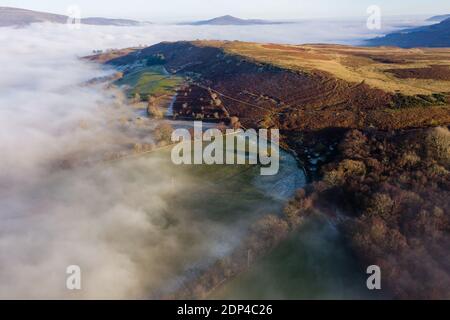 Luftaufnahme von einer frostigen, gefrorenen ländlichen Landschaft aus dem Nebel (Wales, Großbritannien) Stockfoto