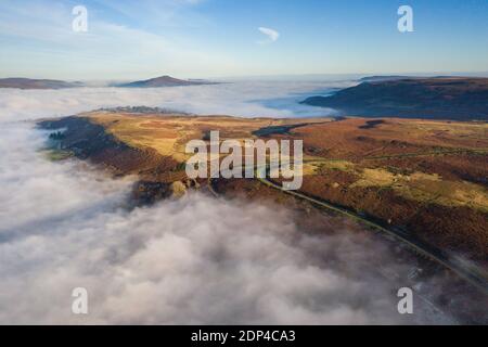 Luftaufnahme einer schmalen, kurvenreichen Bergstraße, die an einem kalten, frostigen Tag durch eine Nebelbank und niedrige Wolke auftaucht (Wales) Stockfoto